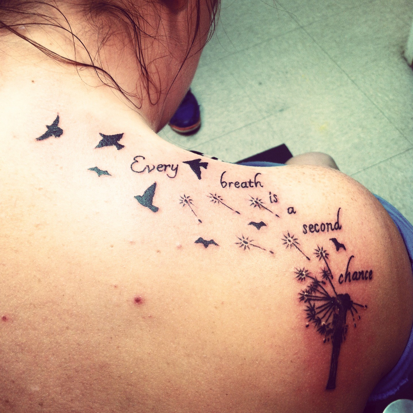 Bird tattoo design with a quote and music notes on woman's back.