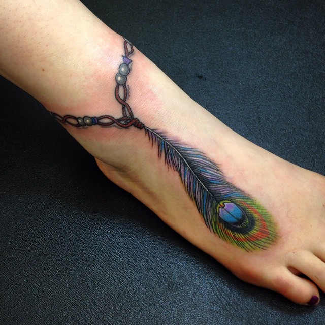 Peacock Feather Tattoo on a woman's leg.