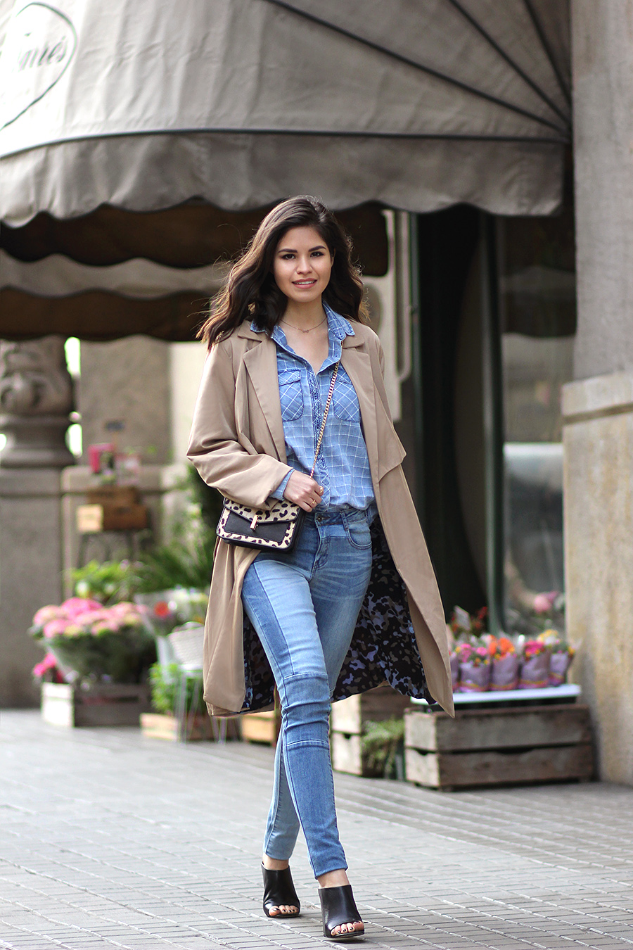 The model in double denim skinny jeans with mules and coat.