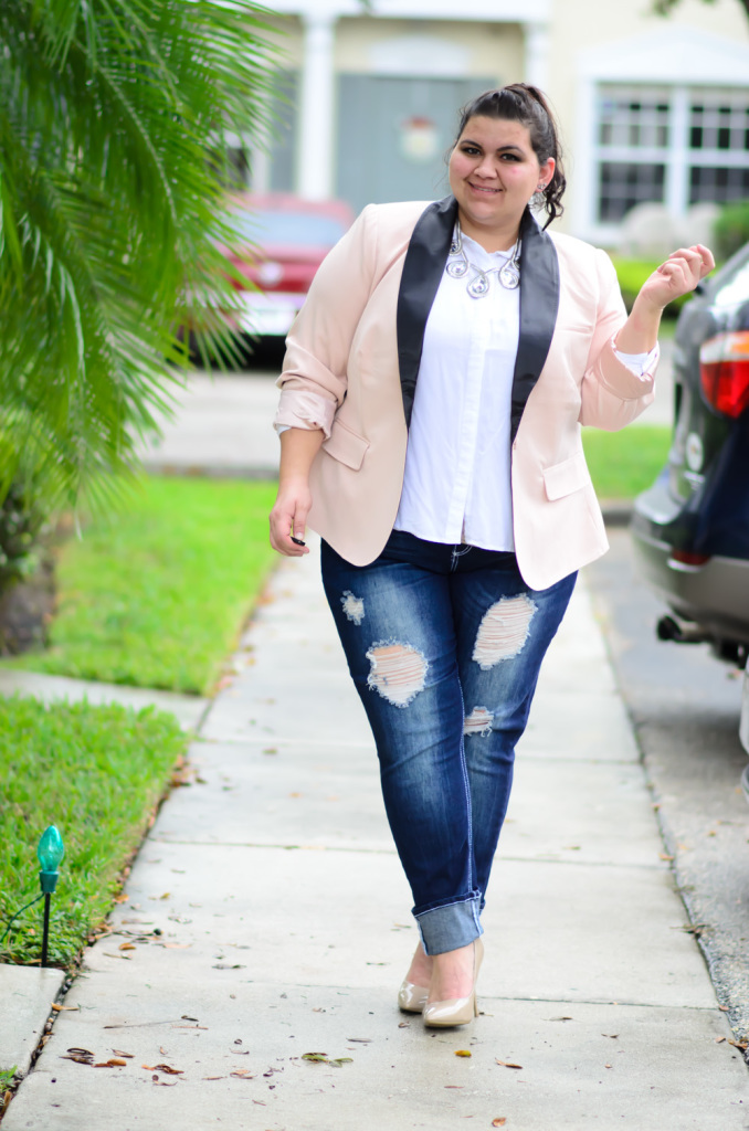 The model in plus size outfit with pink blazer, white shirt and ripped jeans.